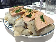 Sliced chả lụa served over bánh cuốn, and garnished with fried shallots
