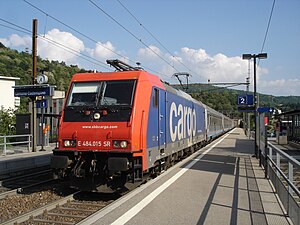 Red-and-blue locomotive on double-track with side platforms