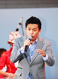 Tùng performing on stage, with blond hair and a white suit