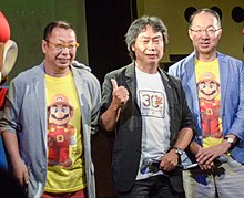 An image of the three integral staff who worked on the game: director Takashi Tezuka, producer Shigeru Miyamoto, and composer Koji Kondo.