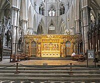 A golden altar and screen in the centre of a grey stone church