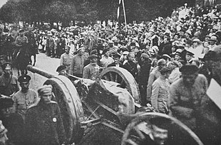 Photo of a scene during the Latvian War of Independence in Northern Latvia, with artillery battery strolled around, and a flag waved from the back.