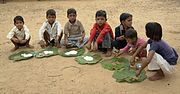 Schoolchildren in Chambal, Madhya Pradesh eating a mid-day meal. The Mid-Day Meal Scheme attempts to lower rates of childhood malnutrition in India.