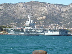 Le Charles de Gaulle à quai à Toulon avec le Mont Faron en arrière-plan.