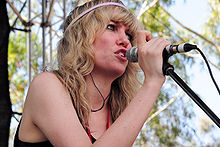 Une femme blonde chantant devant un micro.
