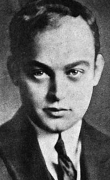 A young white man with dark eyes, receding hairline and dimpled chin, wearing a suit and tie