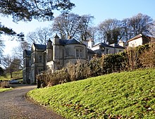 Photograph of sandstone mansion in green, leafy surrounds