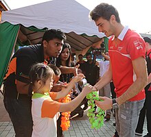 Photo de Jules Bianchi recevant un collier de fleurs de la part d'une fillette, en Malaisie