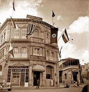 דגל צלב קרס מונף בחזית מבנה מלון פאסט ברחוב יפו בירושלים, 1933.