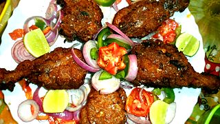 Fried chicken garnished with lemon and onion