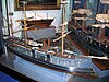 A model of a three-masted warship with two funnels, side by side, and a ram bow