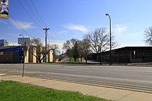 A carless road run approximately perpendicular to another carless road, separated by a boulevard with trees on a sunny, clear day.