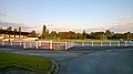 Terrain de football en herbe avec une tribune sur la gauche et une aire de lancer pour l'athlétisme en fond.