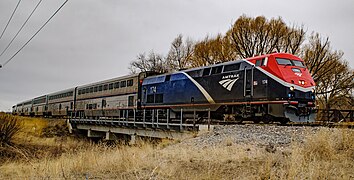 A blue diesel locomotive with an angular white stripe, red nose, and a red sill stripe