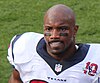 An African-American football player without a helmet on. Mouthgear and eyeblack are visible