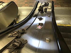 A set of escalators with bronzed gloves scattered in the area between the two.
