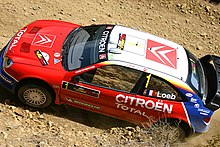 Vue aérienne de la Citroën Xsara WRC de Sébastien Loeb sur un sol en terre.