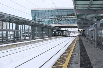 Tågperrongen med stationsbyggnaden synlig.