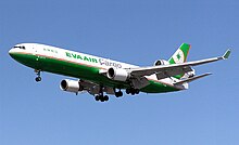 Side view of tri-jet aircraft in flight, with deployed landing gear