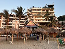 Photograph of a beach club in the foreground and multi-level buildings in the background
