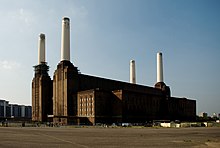 Photo of a large brick building with four tall chimneys, one at each corner.