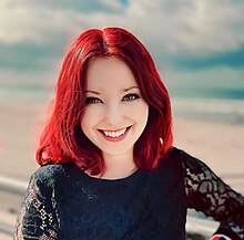 smiling womean with red hair and blue blouse