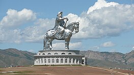 A gigantic statue of a man on a horse stands on top of a building.