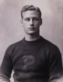 Black-and-white photo of the upper half of a young man wearing a sweater with a large "P" on the front