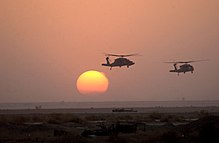 Far away photo of two helicopters in front of the setting sun in Iraq.