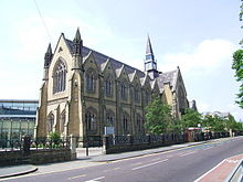 imposing neo-Gothic sandstone chapel, with modern buildings in the background