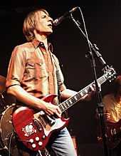 A male guitarist and singer, Mark Arm, is onstage, holding an electric guitar.