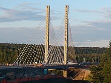 A cable-stayed bridge with a backdrop of coniferous forest