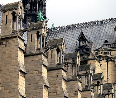 Na Notre-Dame de Paris, os contrafortes maciços se contrapõem ao impulso externo das abóbadas em cruzaria da nave.