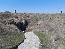 Rocky opening to the cave on a grassland