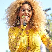 A picture of a blonde woman wearing a yellow outfit performing.