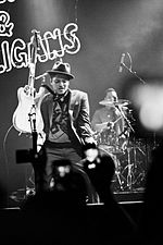 A black and white photograph of Bruno Mars performing with his band at a concert