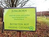 Schild am Rande des Geländes, im Hintergrund ein Informationsrondell