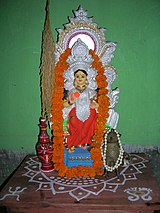 Alpana on an altar underneath a statue of the goddess Lakshmi