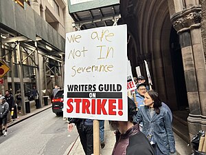 Picket line formed by writers on strike in New York City on location of Daredevil: Born Again. The picket sign references the television series Severance, the production of which was shut down due to the strike.