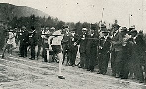 Runner on track, with spectators in formal attire