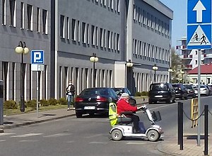 Disabled woman riding a bicycle path in an electric wheelchair, Tomaszów Mazowiecki, Saint Anthony Street, 2020