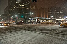 Rue de New York remplie de neige, photographiée dans la nuit.