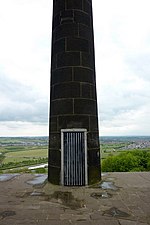 Une porte dans une colonne de pierre, recouverte d'une grille métallique