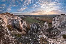 Monts de rochers blancs et pointus, avec une campagne derrière.