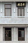 A 2008 closeup of the sign hanging outside the 2nd floor of the building. A North Korean soldier is seen guarding the first floor entrance.)