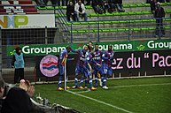 Photographie de joueurs de football célébrant un but au poteau de corner.