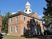 A photo of a colonial courthouse with brick walls and a white clock spire