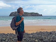 Foto do professor Paulo da Cunha Lana na praia com uma mochila nas costas