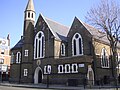 The former St Barnabas Church, Kentish Town Road, Camden in London, 1884–85 by Ewan Christian, now the Greek Orthodox Cathedral of St Andrew, showing the west front with north apse and turret[158]