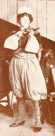 A white woman standing, holding a gun, wearing a costume with voluminous knee britches and wide sleeves